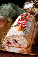 Festive Christmas meringue roll with cherries on table.