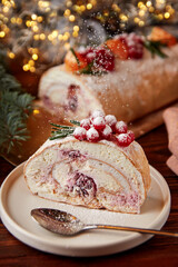 Slice of meringue roll with cherries decorated for Christmas.