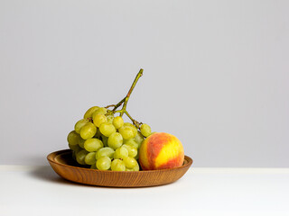 Fruits-grapes, peach, dogwood berries on a milky white background and gray background, close-up.