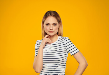 pretty woman in striped t-shirt gesturing with hands joy yellow background