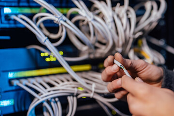 Technician stripping insulation on ethernet cable, close-up.