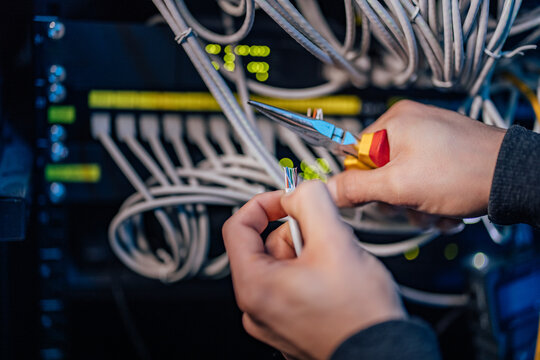 Male hands holding ethernet cable and pliers, close-up.