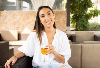 Smiling young woman drinking beer in a terrace