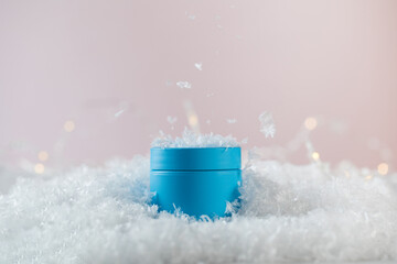Bright blue blank jar of winter protective cosmetic product in artificial snow 