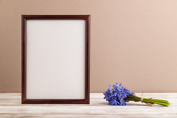 Wooden frame with spring snowdrop flowers bluebell on beige pastel background. top view, copy space, mockup, template.