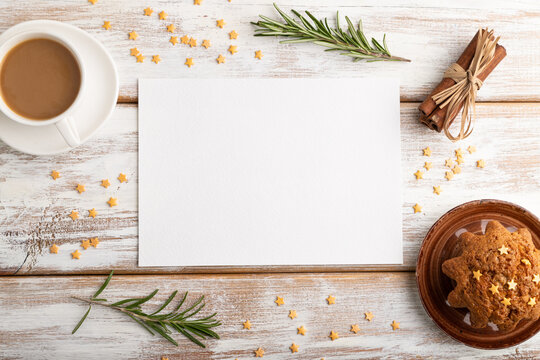 White paper sheet mockup with cup of coffee and cake on white wooden background. top view