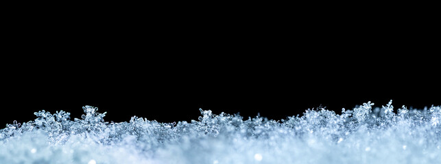 Natural snow texture with snowflakes close-up, isolated on black background with space for text on...