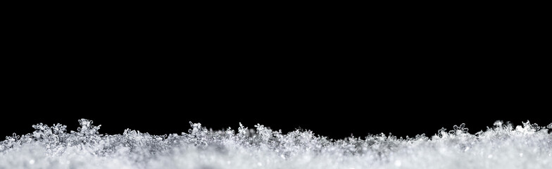 Natural snow texture with snowflakes close-up, isolated on black background with space for text on top. Template for holiday gift cards. Macro texture of snow. Big large size.