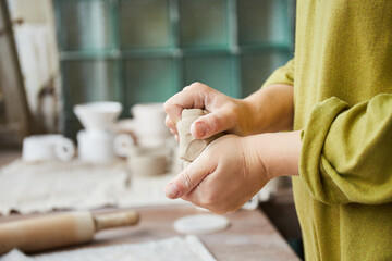 Fototapeta premium Female ceramist working in pottery studio. Ceramist's Hands Dirty Of Clay. Process of creating pottery. Master ceramist works in her studio