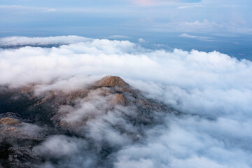 View from above, stunning aerial view of a granitic massif surrounded by white, fluffy clouds during a beautiful sunrise. Mount Limbara (Monte Limbara) Sardinia, Italy.