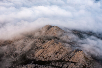 View from above, stunning aerial view of a granitic massif surrounded by white, fluffy clouds during a beautiful sunrise. Mount Limbara (Monte Limbara) Sardinia, Italy.