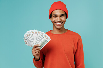Young smiling happy african american man 20s in orange shirt hat holding fan of cash money in...