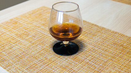 a glass of whiskey is on a wicker napkin on the table