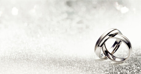 Shiny silver rings on white background with glowing glitter