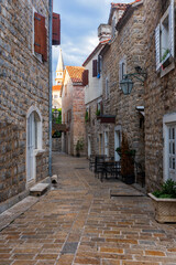 Fototapeta na wymiar Ancient stone street in Budva, Montenegro. Narrow streets and a view of the ancient citadel. Fort on the Adriatic Sea.