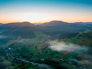 Fog in the mountain valley at dawn. Ukrainian Carpathians in the morning in the haze. Aerial drone...