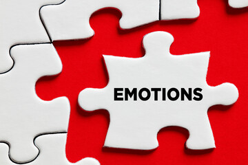 Fototapeta premium The word emotions on a puzzle piece with red background. Emotional complexity or confusion
