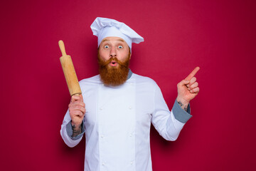 amazed chef with beard and red apron chef holds wooden rolling pin
