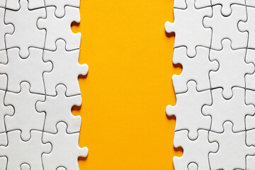 Blank yellow background surrounded by white jigsaw puzzle pieces with copy space.