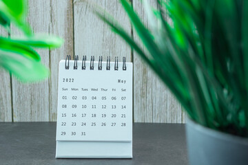 White May 2022 calendar with potted plant on a desk. New Year Concept