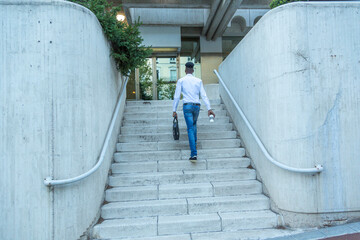 portrait young black businessman climbing stairs with briefcase in hand