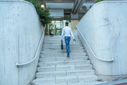 portrait young black businessman climbing stairs with briefcase in hand