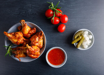 wood smoked chicken. Homemade wood smoked chicken legs with french fries and chili sauce on the side. Top view. On a dark wood table top.