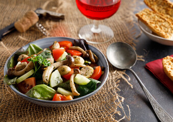 mushroom salad in a bowl. Summer meal a salad with himeji, oyster fungus, white Paris mushrooms mixed with young lettuce, tomatoes and cucumber.