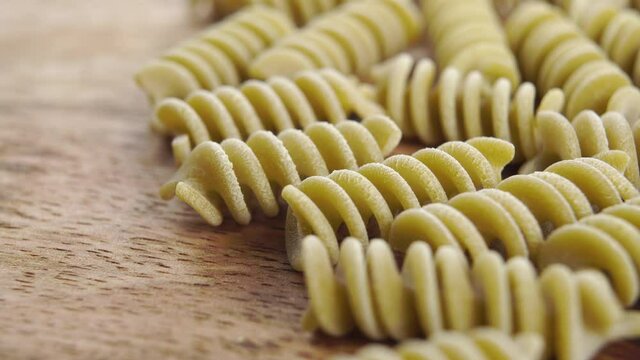 Green vegetable raw italian fusilli pea pasta on a wooden background. Macro. Dolly shot.