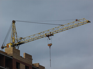 Yellow crane on the background of a building under construction.