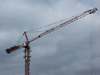 Modern tower crane on the background of the cloudy sky.