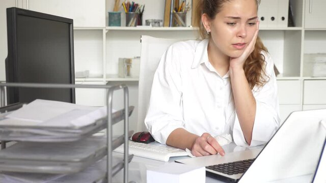 Tired young woman secretary sitting alone near laptop computer and upset after receiving mail 