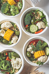 Vegan vegetable salad in paper take away bowls. Eco-friendly recyclable tableware, zero waste concept.