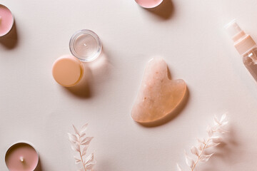 Guashe scrapes from rose quartz  and cosmetic product bottle of cream Natural stone massager for face