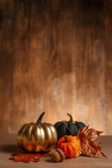 Decorated golden, black and natural pumpkins on wooden background