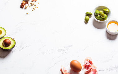 Keto diet ingredients frame on white marble background, copy space. Low carbohydrate menu concept.