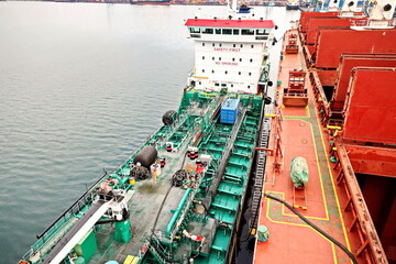 Bunkering operations at the port. Bunker barge alongside of the vessel. Port of Vostochnyy. Russia, December, 2020.