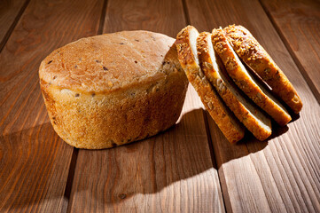 A loaf of delicious white bread made from natural products, on hops with flax saturation, without baker's yeast, on a wooden table surface.