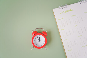 top view of red analog alarm clock and blurred annual calendar for appointment, meeting, planning...