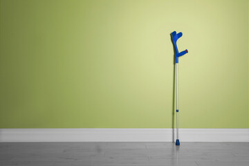 Elbow crutch near light green wall. Space for text