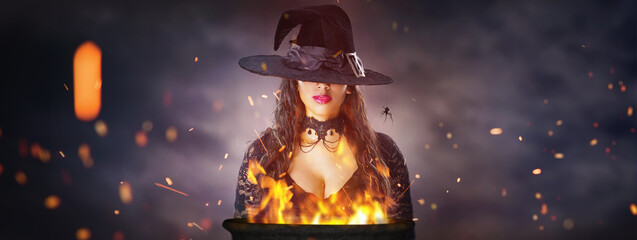 Halloween Witch with a cauldron. Beautiful young woman in witches hat conjuring, making witchcraft....