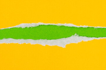 Hole in yellow paper background to reveal hidden green paper