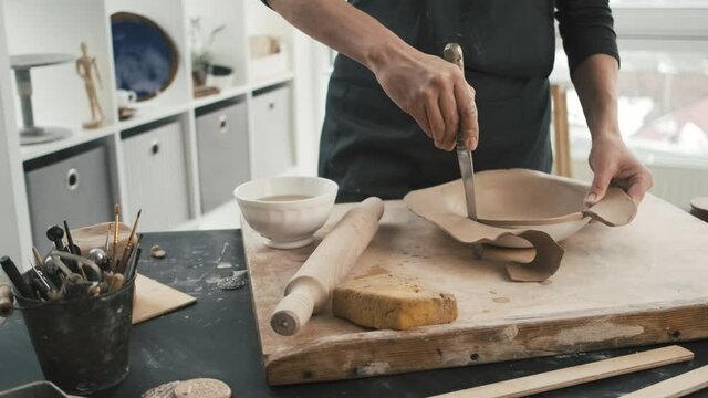 Potter cut excess clay modeling craft plate during ceramic workshop. Closeup view of making earthenware