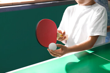Little boy playing ping pong indoors, closeup