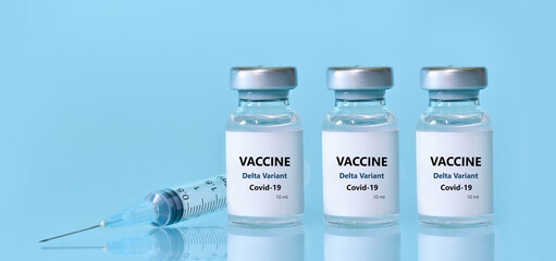 Three vials with a vaccine, a syringe on a blue background.The concept of medicine, healthcare and science.Coronavirus vaccine.Copy space for text..Banner