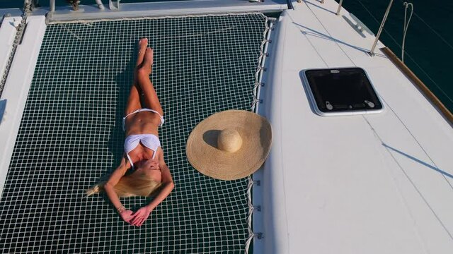 Woman in bikini tanning and relaxing on a summer catamaran sailing cruise
