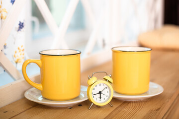 Two yellow cups with a clock in the middle
