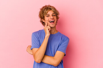 Young caucasian man with make up isolated on pink background smiling happy and confident, touching chin with hand.