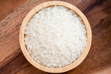 Rice grains in wooden bowl on wooden background, Japanese rice grains in wooden bowl on wooden background.