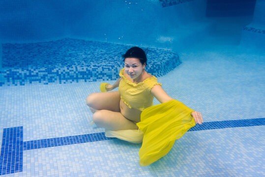 Pregnant woman swim, dive in swimming pool. Aqua fitness healthcare classes for pregnancy. Underwater picture of pregnant woman wearing fashion dress in blue deep pool. Aquatic therapy workout.